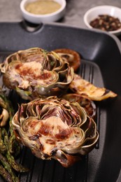 Photo of Tasty grilled artichoke and asparagus on table, closeup