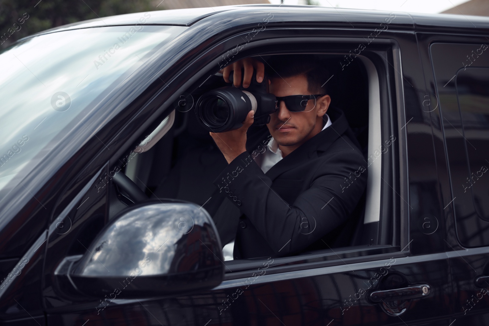 Photo of Private detective with camera spying from car