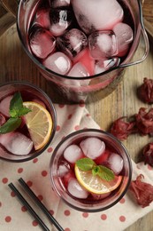 Photo of Delicious iced hibiscus tea, dry flowers and straws on wooden tray, flat lay