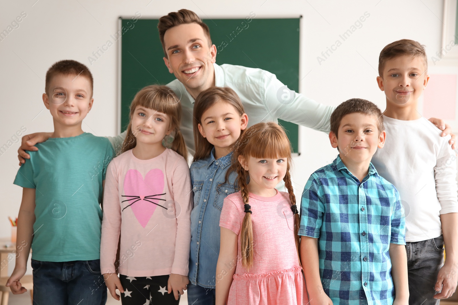 Photo of Cute little children with teacher in classroom at school