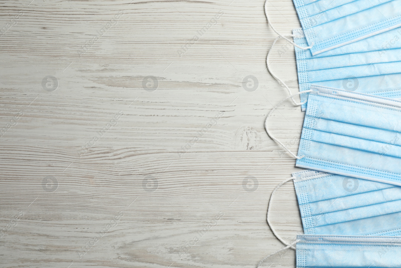 Photo of Protective masks on wooden background, flat lay with space for text. Safety equipment