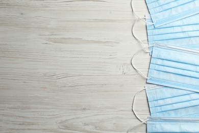 Protective masks on wooden background, flat lay with space for text. Safety equipment