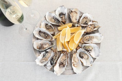 Photo of Fresh oysters with cut juicy lemon served on table, top view