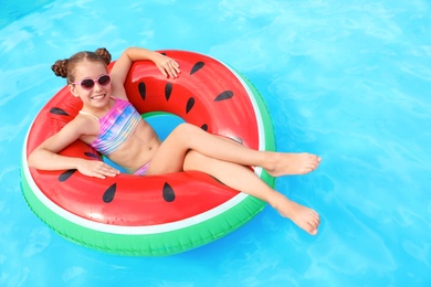 Little girl with inflatable ring in swimming pool