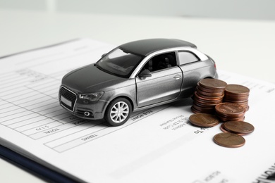 Photo of Toy car, money and insurance contract on table