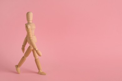 Photo of Wooden human model on pink background, space for text. Mini mannequin