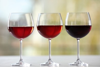 Photo of Different sorts of wine in glasses on table