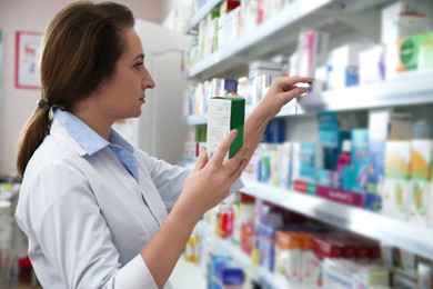Professional pharmacist near shelves with merchandise in modern drugstore