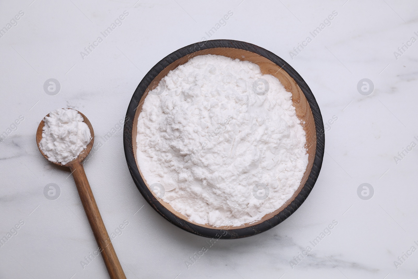 Photo of Wooden bowl and spoon of natural starch on white marble table, flat lay