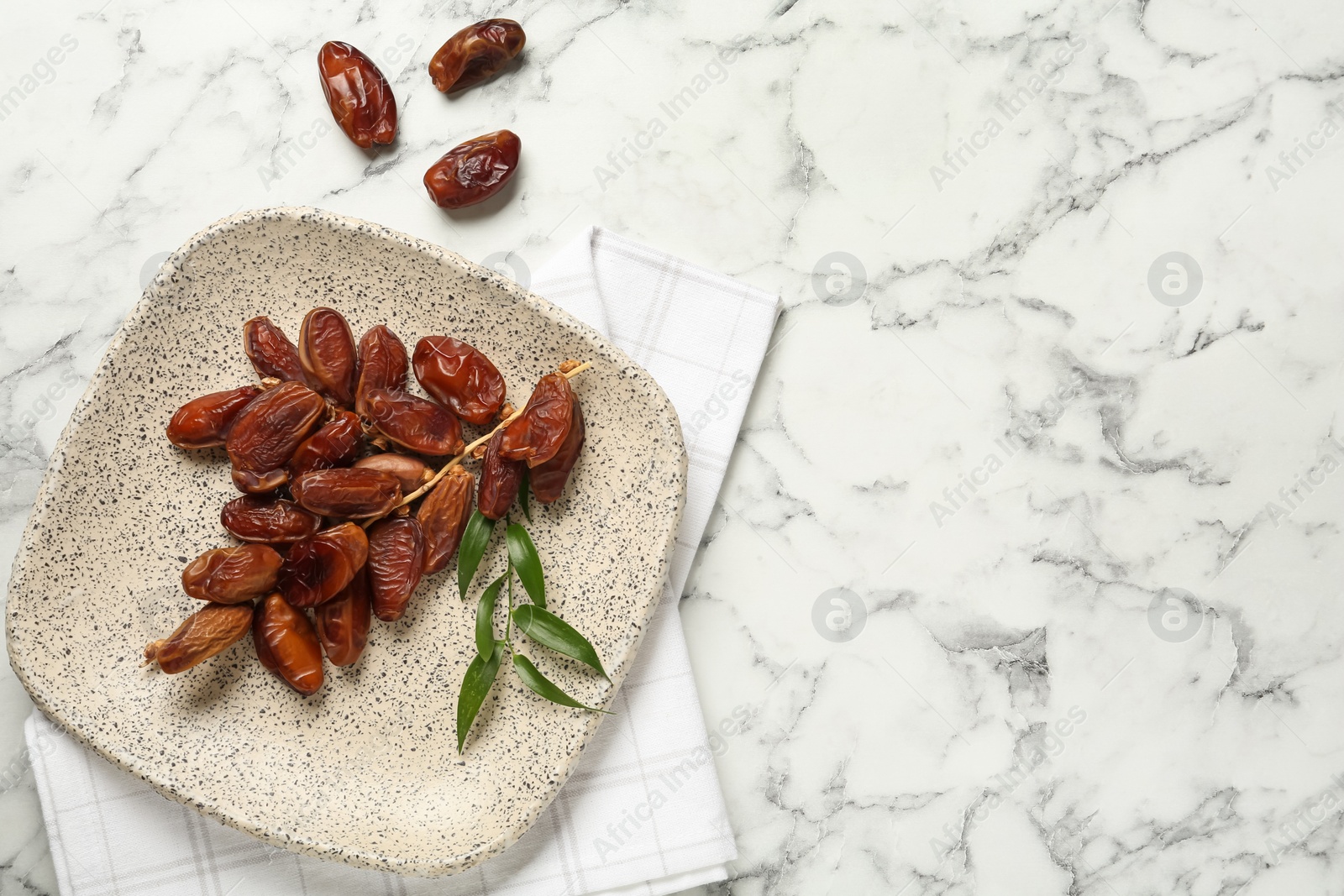 Photo of Plate with sweet dried dates on white marble table, top view. Space for text