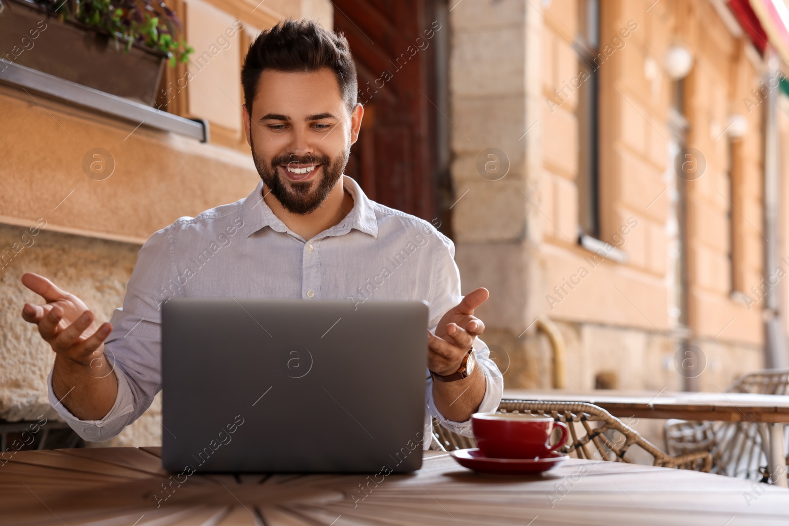 Photo of Handsome man working on laptop at table in outdoor cafe. Space for text