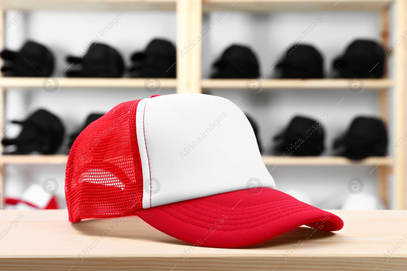 Photo of Blank red and white cap on wooden table in store. Mock up for design