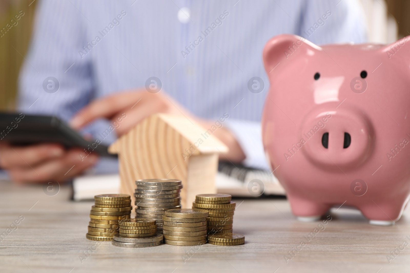 Photo of Savings for house purchase. Woman calculating money at wooden table, focus on coins