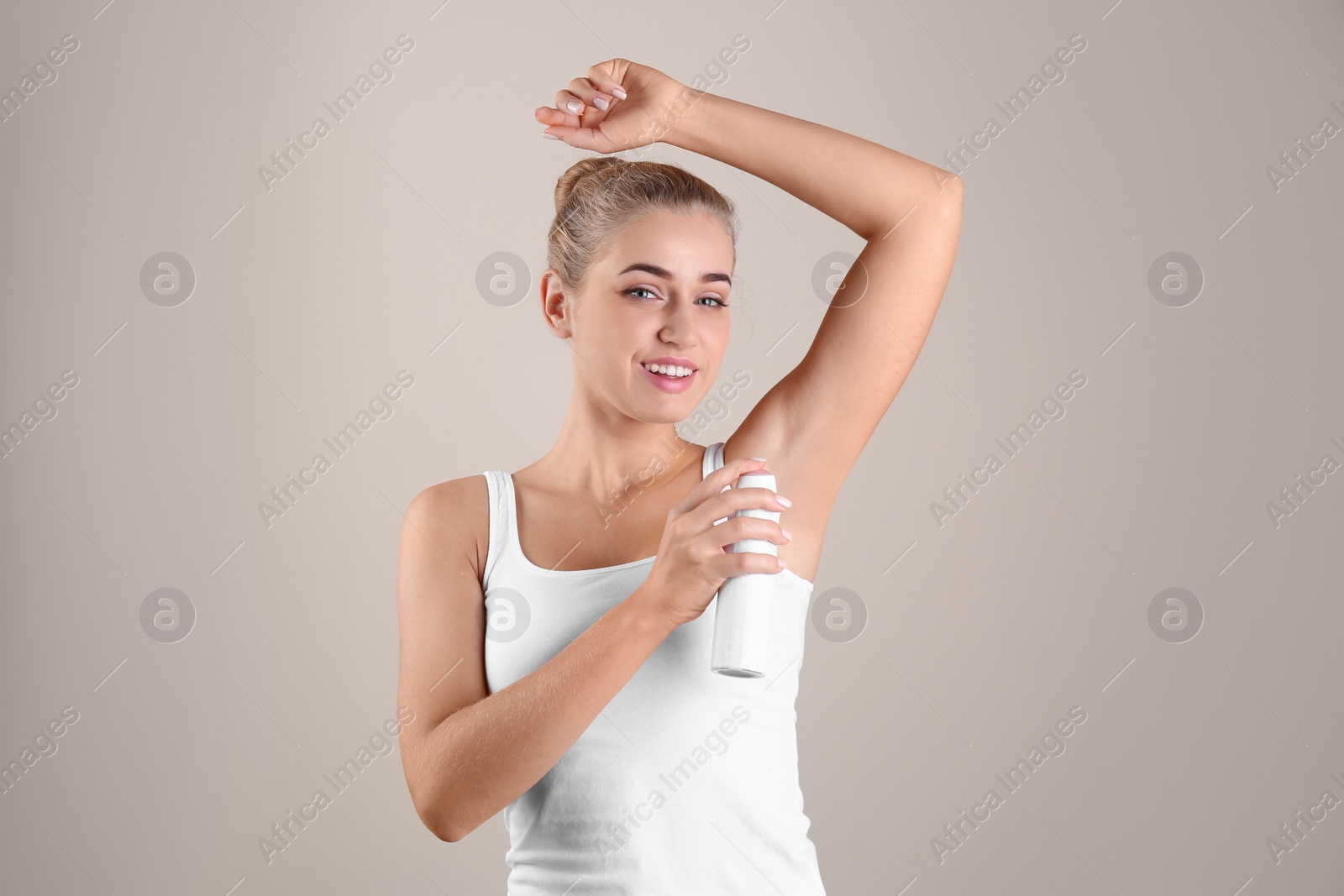 Photo of Young woman using deodorant on color background