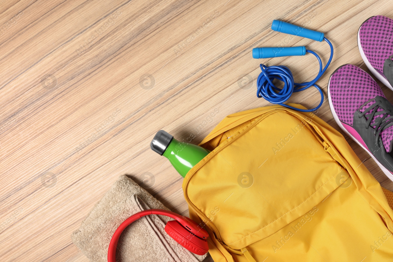 Photo of Flat lay composition with backpack and different sports equipment on wooden surface. Space for text