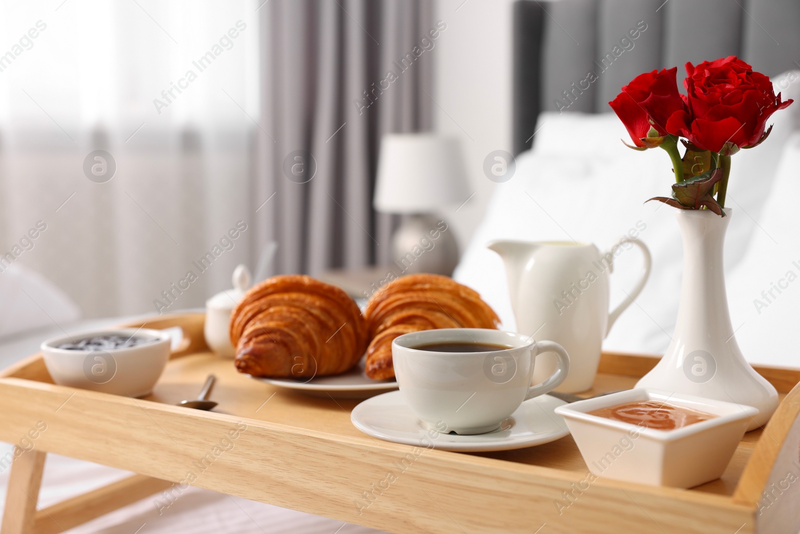 Tasty breakfast served in bed. Fresh croissants, coffee, jam and honey on wooden tray, closeup Photo of Tasty breakfast served in bed. Fresh croissants, coffee, jam and honey on wooden tray, closeup