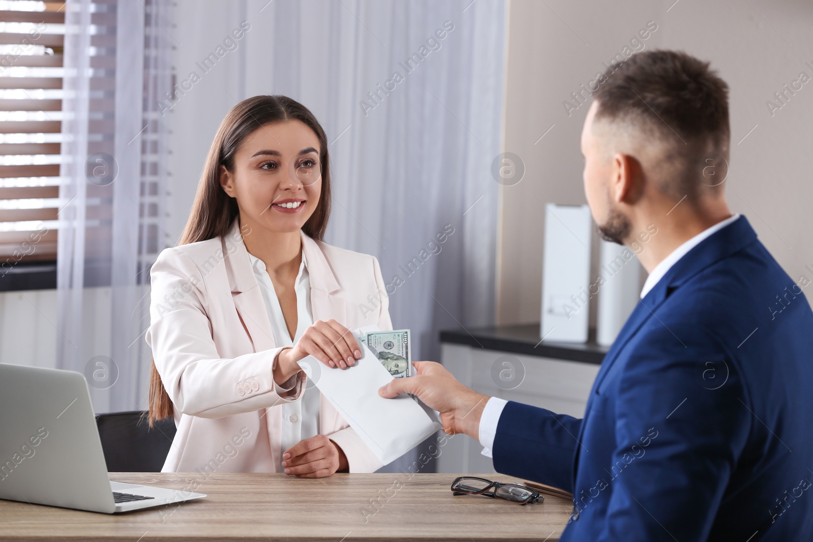 Photo of Man giving bribe to woman at table in office