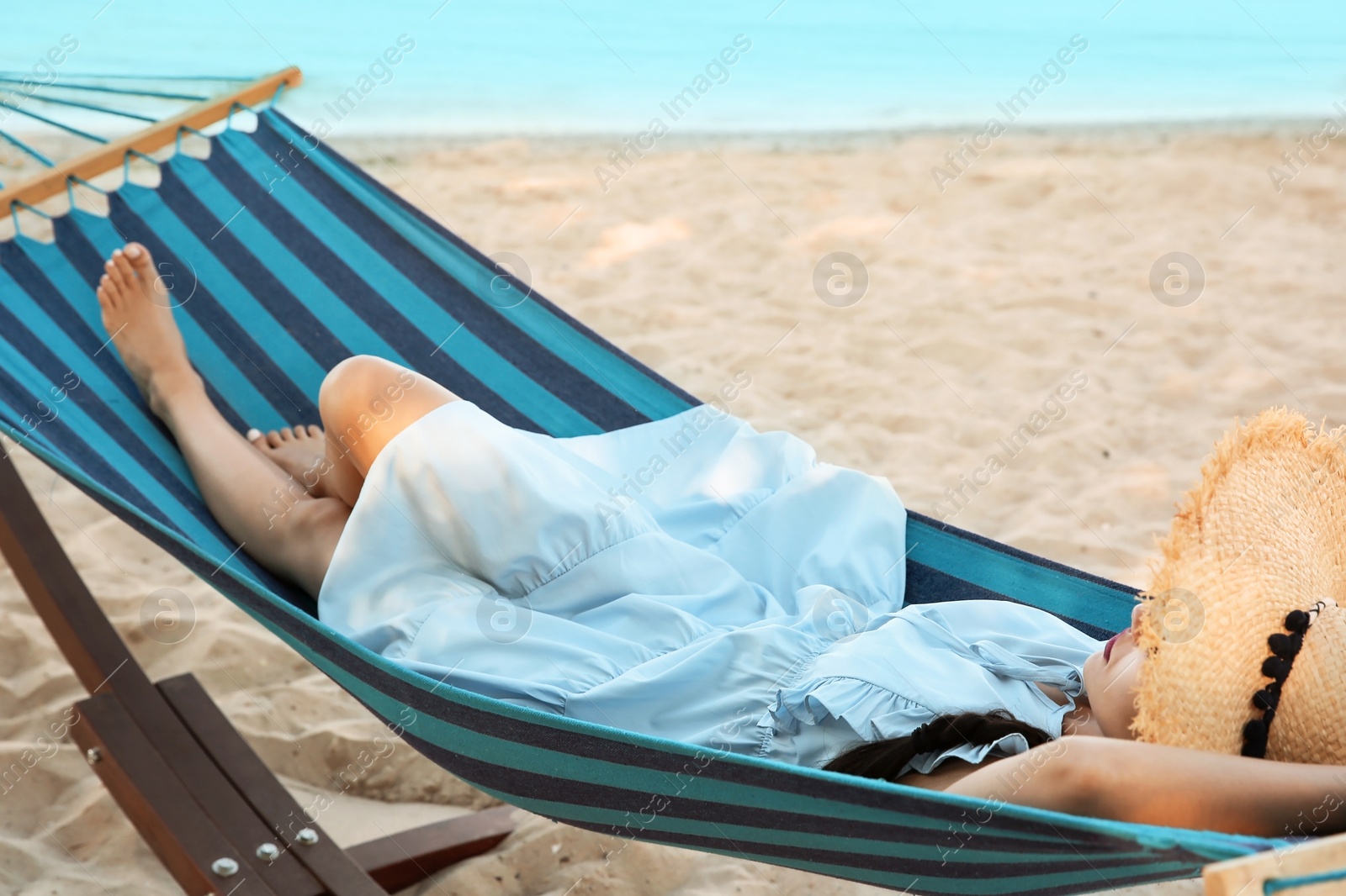 Photo of Young woman resting in comfortable hammock at seaside