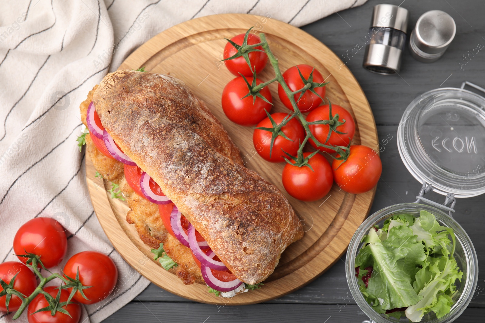 Photo of Delicious sandwich with schnitzel on grey wooden table, flat lay