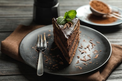 Plate with slice of chocolate cake and fork on wooden table