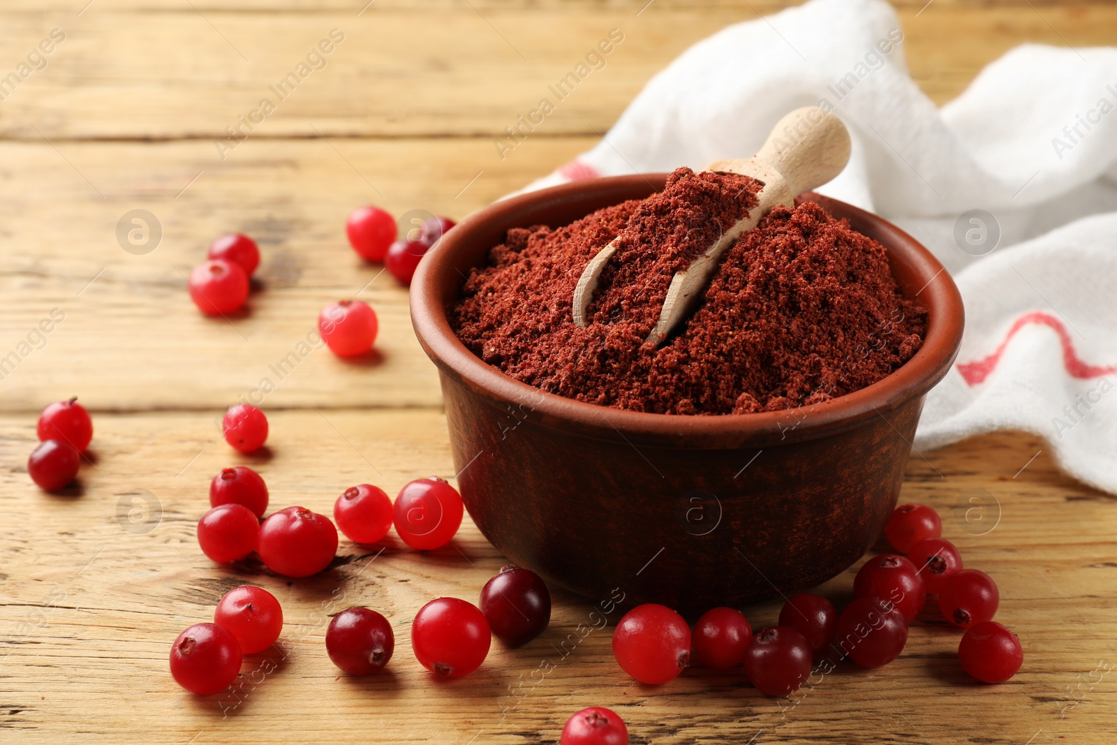 Photo of Cranberry powder in bowl, scoop and fresh berries on wooden table, closeup