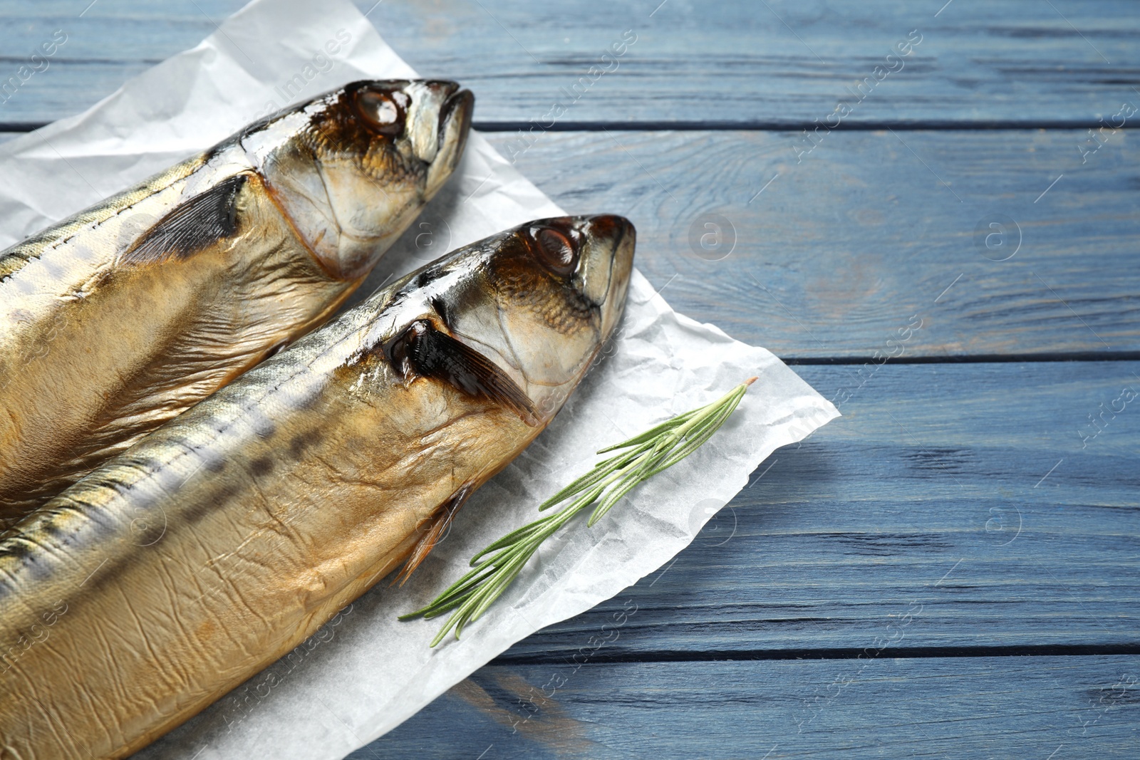Photo of Tasty smoked fish on blue wooden table, closeup