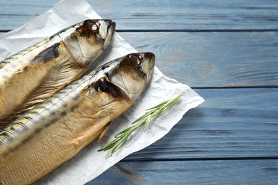 Photo of Tasty smoked fish on blue wooden table, closeup