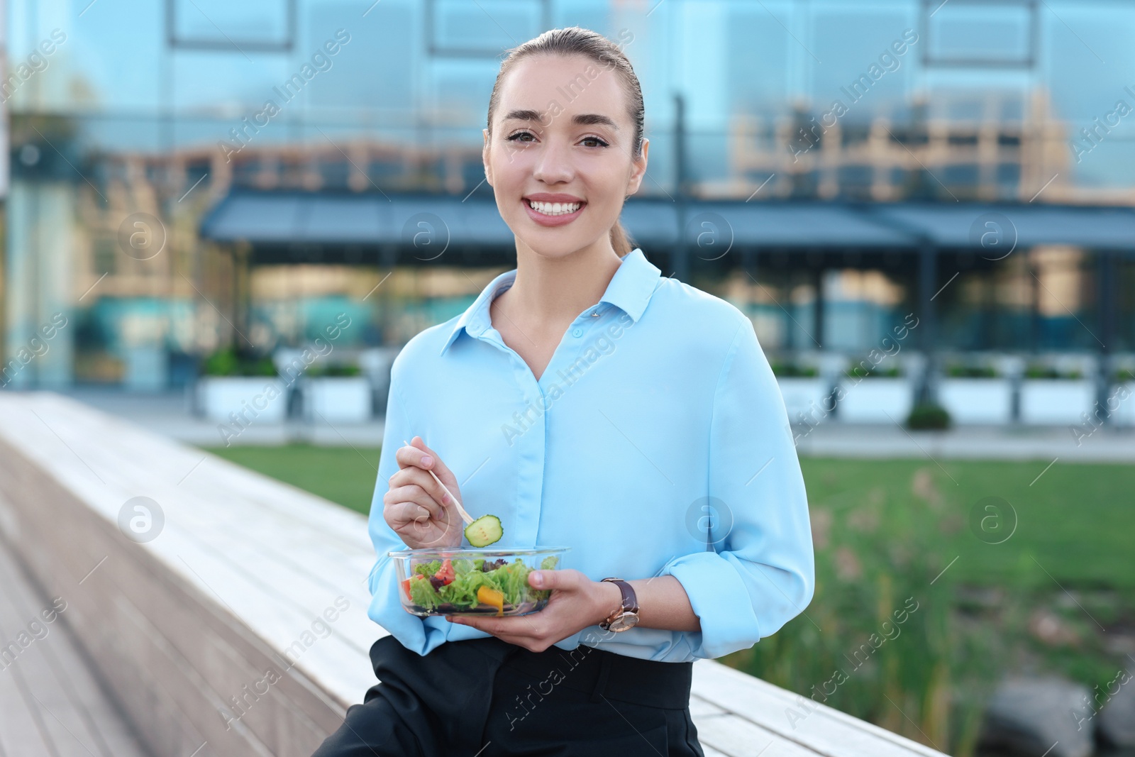 Photo of Portrait of smiling businesswoman eating lunch outdoors