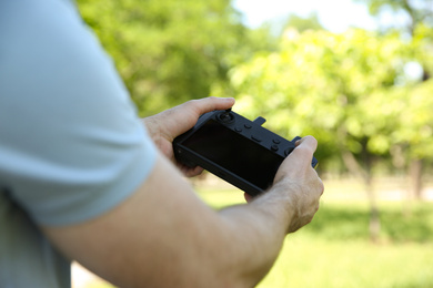 Photo of Man holding new modern drone controller outdoors, closeup of hands