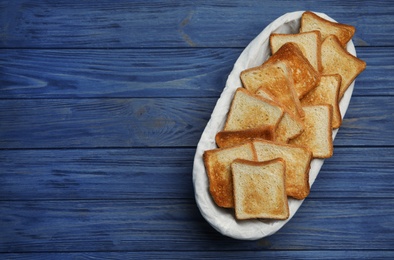 Photo of Basket with toasted bread on blue wooden table, top view. Space for text