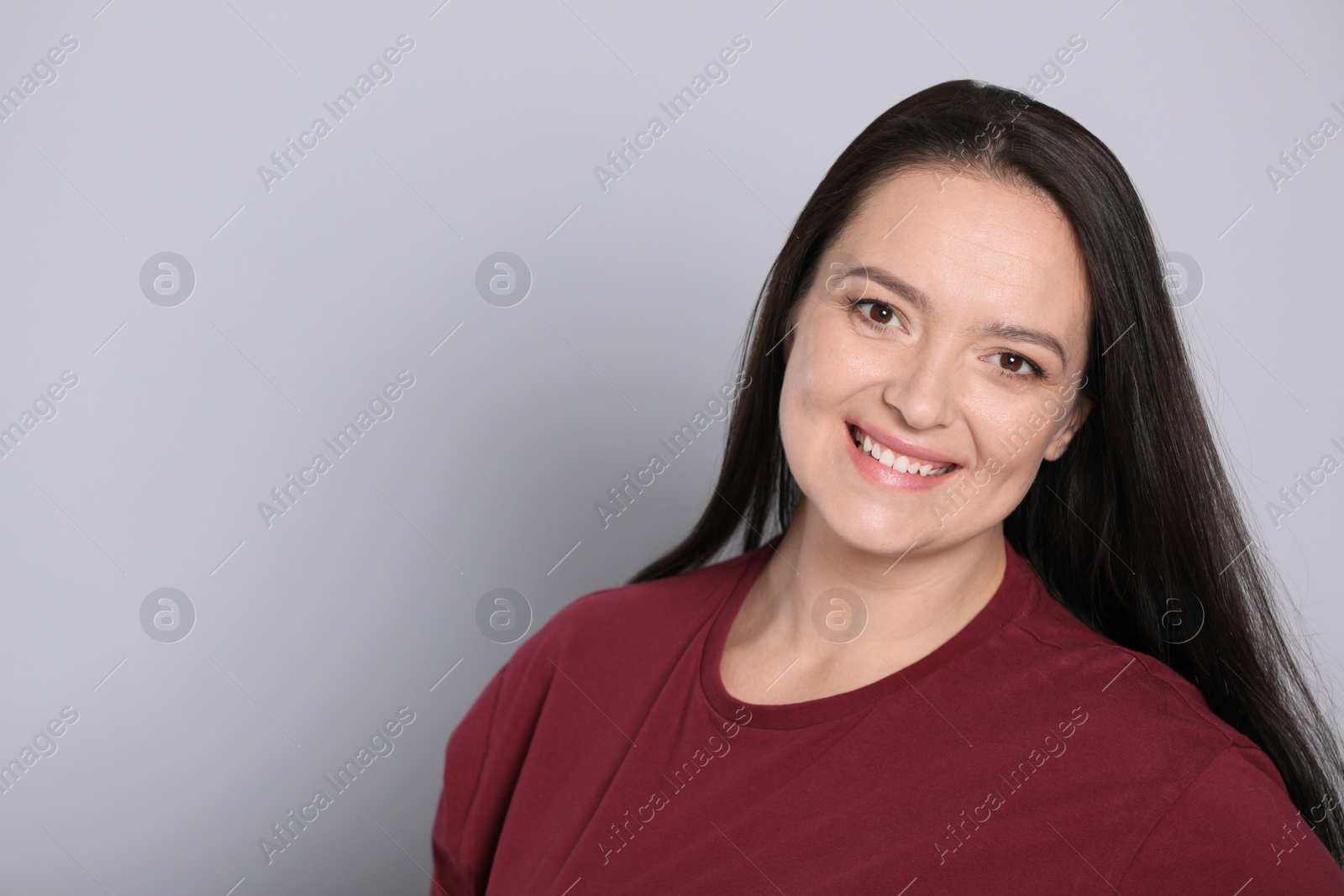 Photo of Beautiful overweight woman with charming smile on light grey background. Space for text