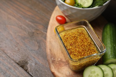 Tasty vinegar based sauce (Vinaigrette) in bowl and products on wooden table, closeup. Space for text