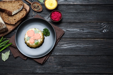 Photo of Delicious homemade chicken aspic served on black wooden table, flat lay. Space for text