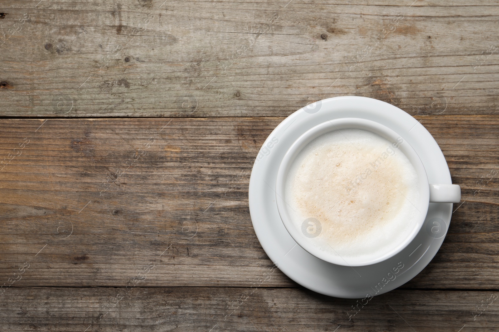 Photo of Aromatic coffee in cup on wooden table, top view. Space for text