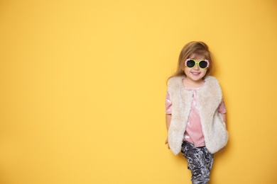 Cute little girl in trendy outfit on color background