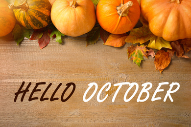 Image of Hello October text, pumpkins and autumn leaves on wooden background, flat lay