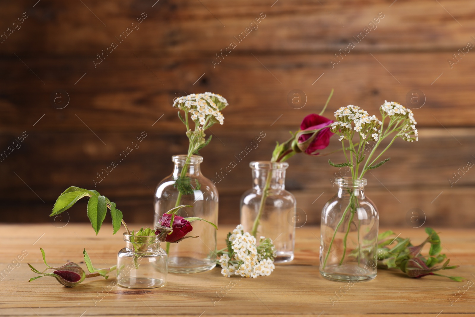 Photo of Different flowers in glass bottles on wooden table