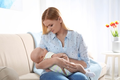 Photo of Mother with her little baby sitting in armchair at home