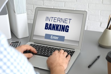 Image of Man using online banking application on laptop at grey table, closeup