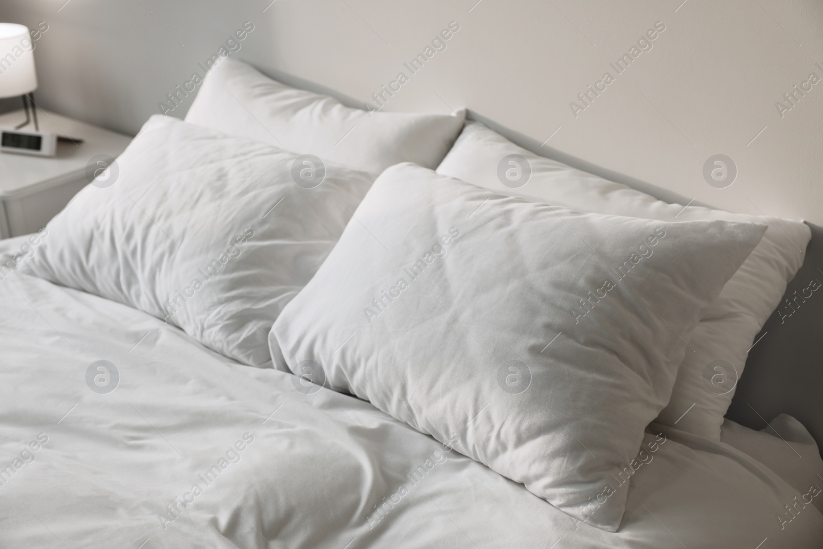 Photo of White soft pillows on bed in room