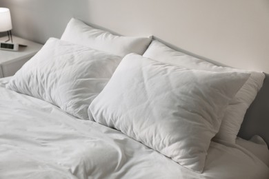 Photo of White soft pillows on bed in room