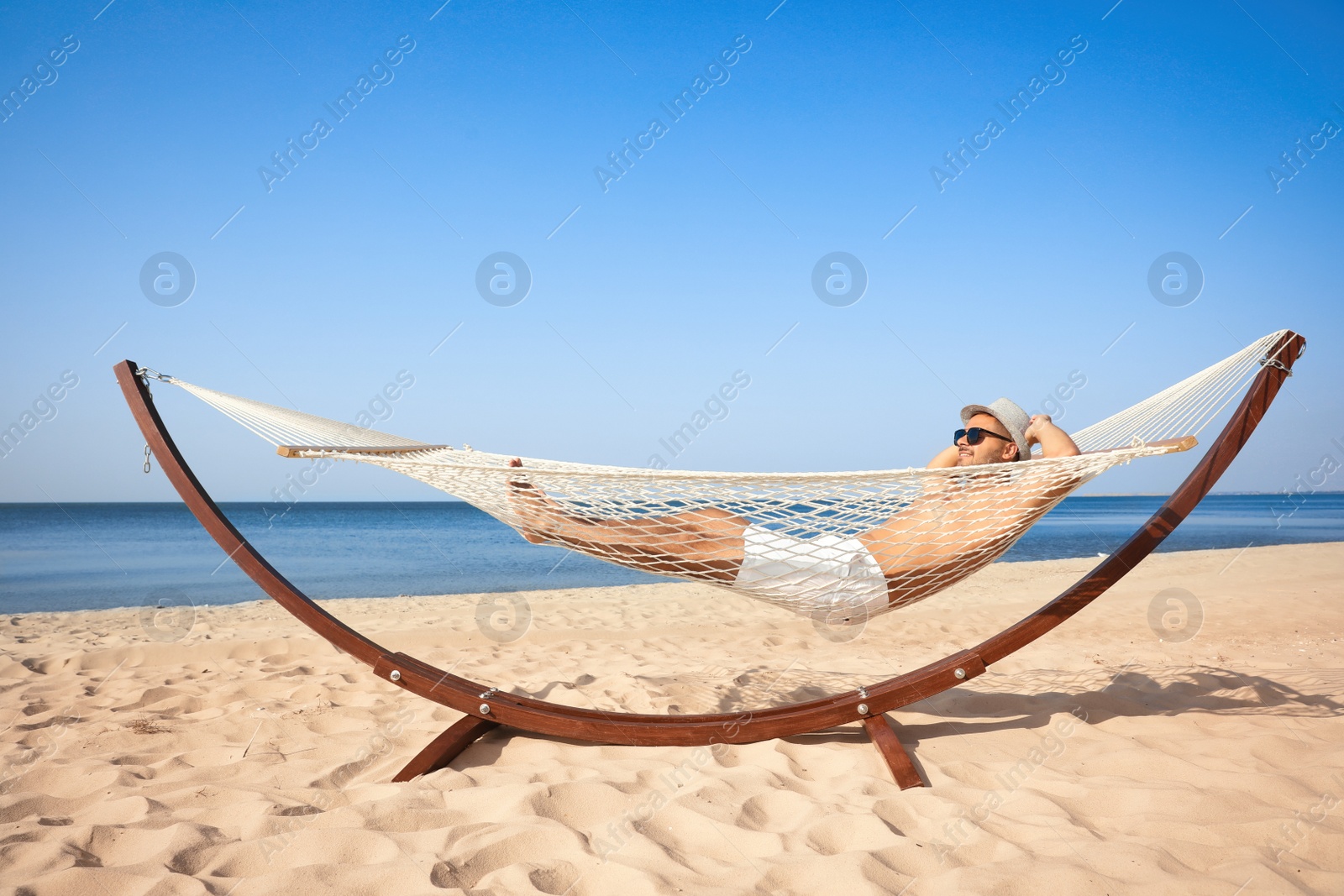 Photo of Young man relaxing in hammock on beach