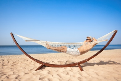 Young man relaxing in hammock on beach