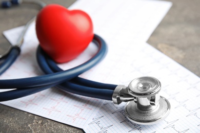 Photo of Stethoscope, red heart and cardiogram on gray table. Cardiology concept