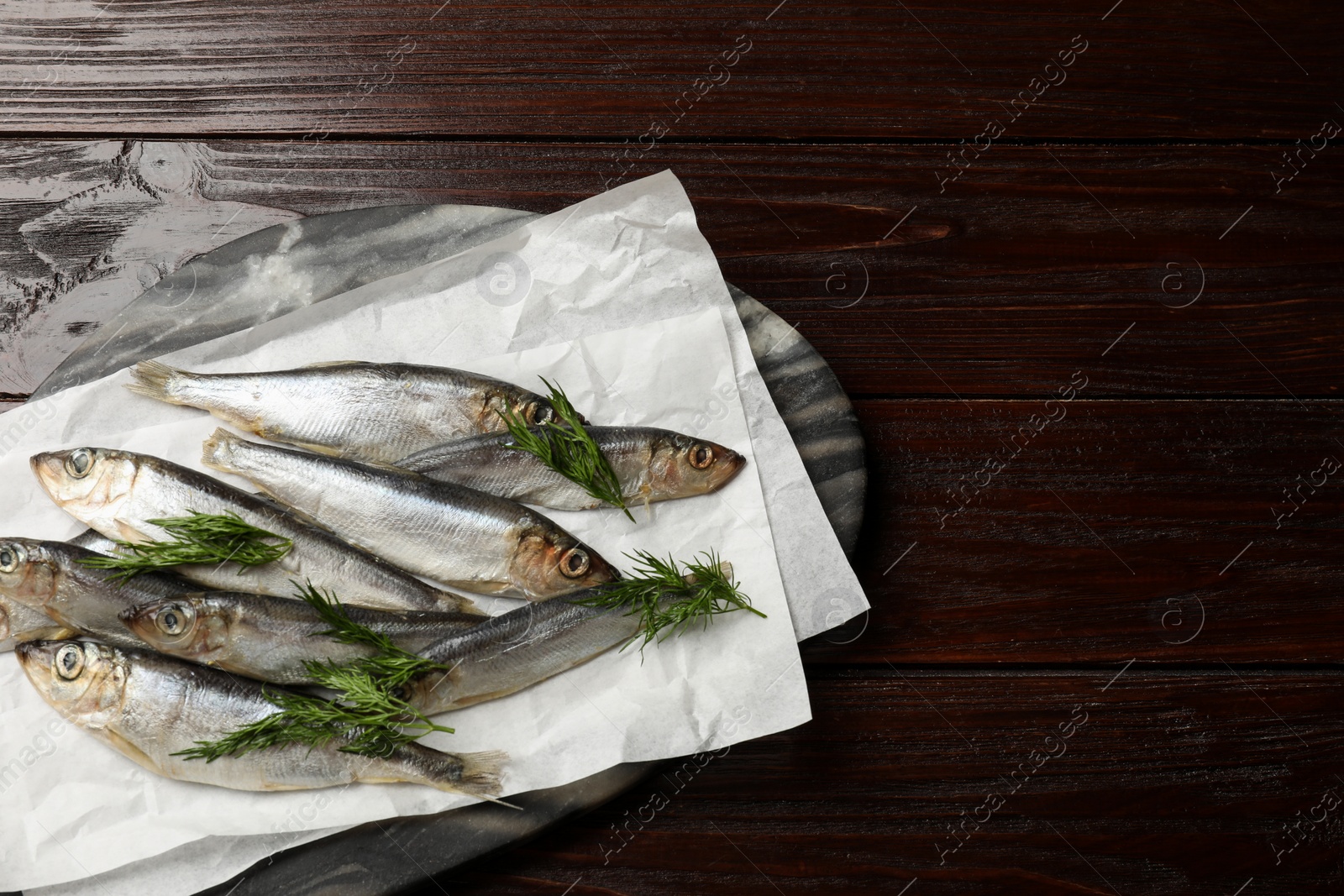 Photo of Fresh raw sprats and dill on wooden table, top view. Space for text