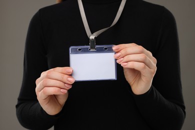 Woman with blank badge on grey background, closeup