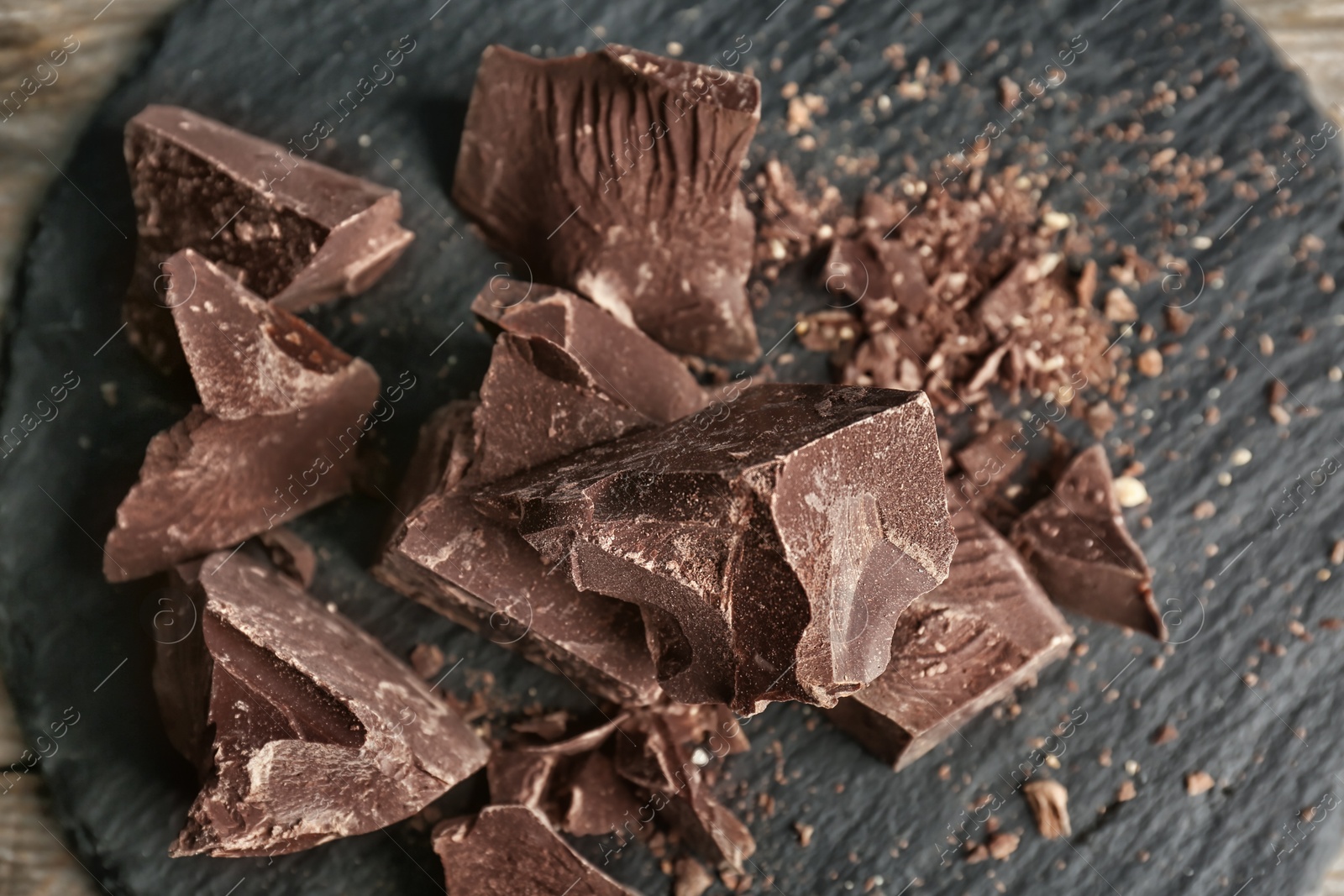 Photo of Delicious dark chocolate on slate plate, top view