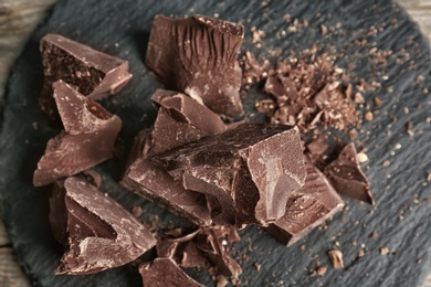 Photo of Delicious dark chocolate on slate plate, top view