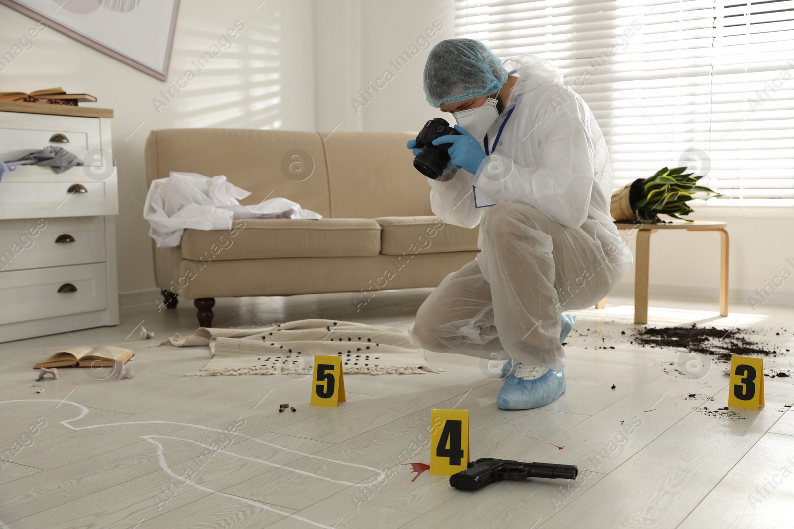 Photo of Investigator in protective suit making photo of crime scene indoors