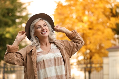 Portrait of happy mature woman with hat outdoors
